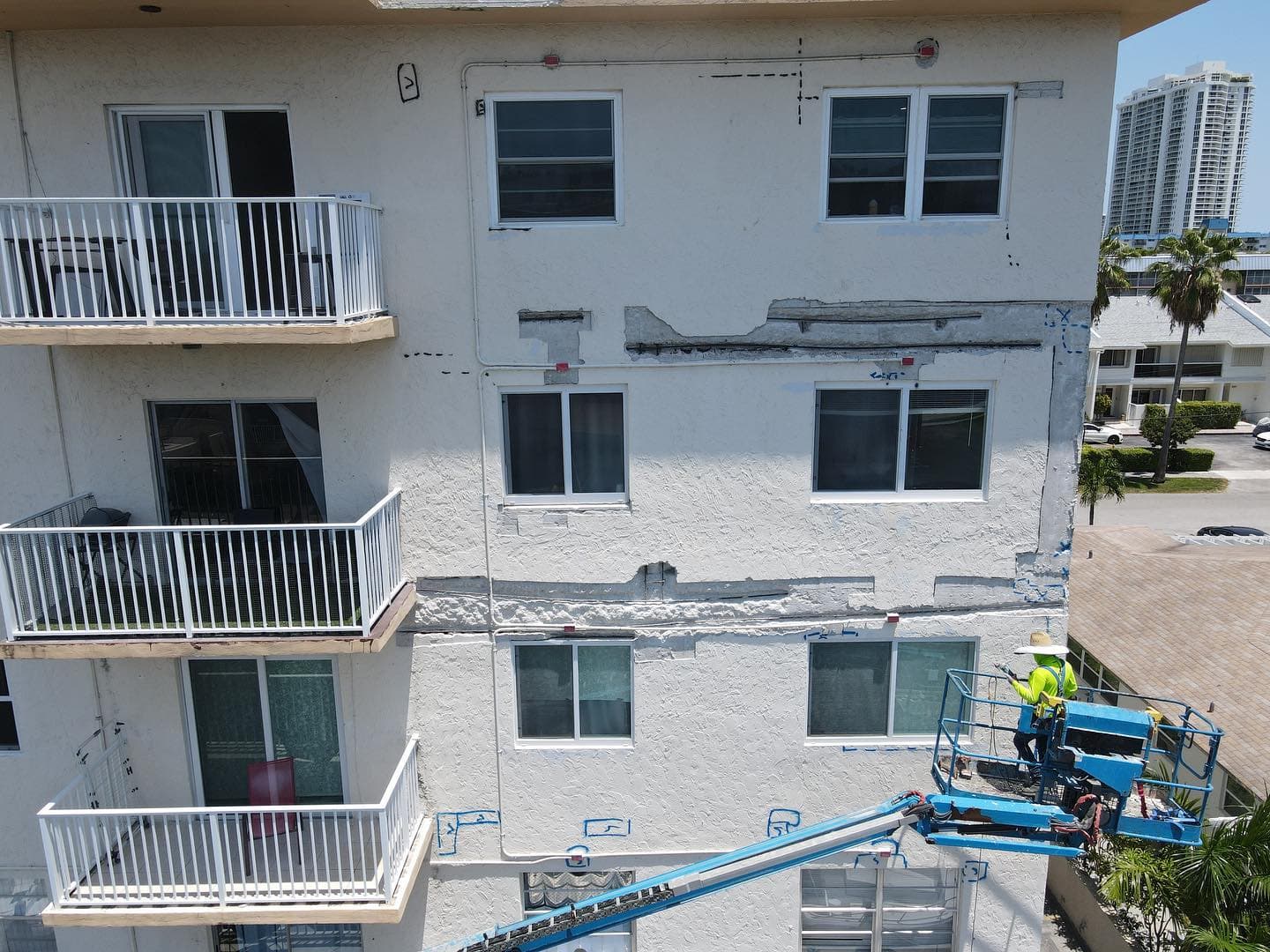 Basile crew in a boom lift making concrete and stucco repairs on a waterfront condo facade