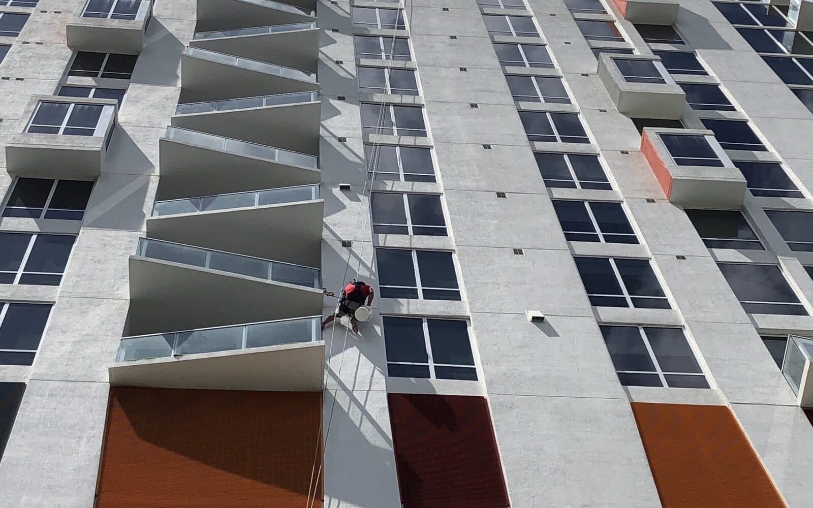 A Basile technician on rope access beside the balconies and rust-coloured panels of The Crimson Condominium in Miami