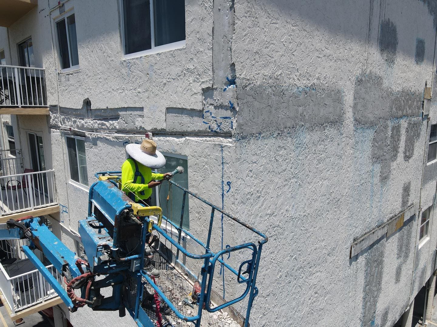 Basile crew member preparing a stucco facade from a boom-lift basket